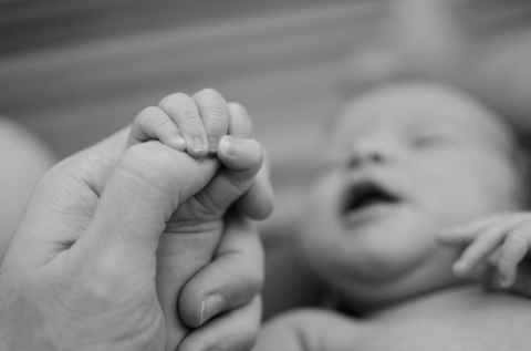 A baby holding an adults thumb